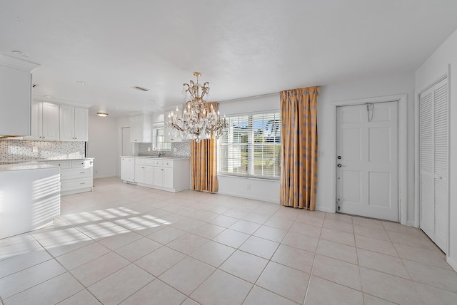 interior space with light tile patterned flooring, a notable chandelier, visible vents, and baseboards