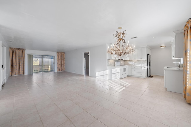 unfurnished living room with a notable chandelier, visible vents, a sink, and light tile patterned flooring
