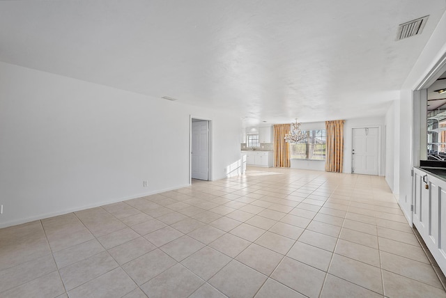 unfurnished living room featuring an inviting chandelier, baseboards, light tile patterned floors, and visible vents