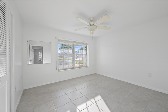 unfurnished room featuring light tile patterned flooring, a ceiling fan, and baseboards