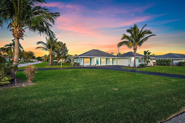 ranch-style house featuring aphalt driveway, a front lawn, and an attached garage