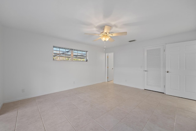 unfurnished bedroom featuring light tile patterned floors, visible vents, baseboards, ceiling fan, and a closet