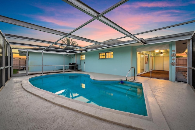 pool at dusk featuring a patio, fence, and glass enclosure