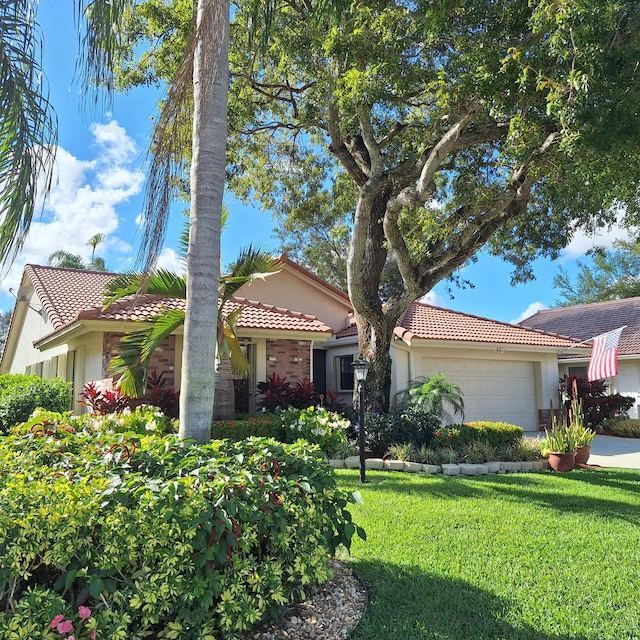 view of front facade featuring a garage, a tile roof, a front lawn, and stucco siding