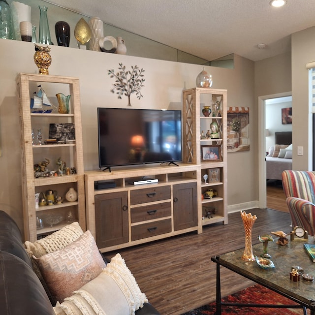living room featuring dark wood-style flooring, vaulted ceiling, and a textured ceiling