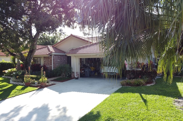 view of front of house featuring an attached garage, brick siding, a tile roof, driveway, and a front lawn