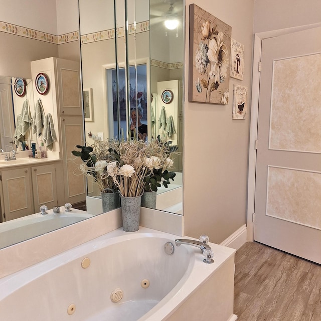 full bathroom with a whirlpool tub, baseboards, wood finished floors, and vanity