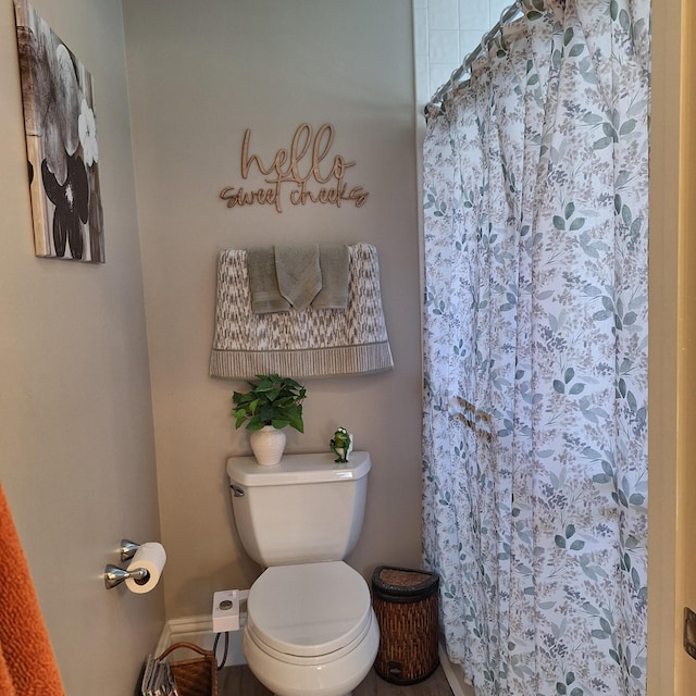 full bath with toilet, a shower with curtain, and baseboards