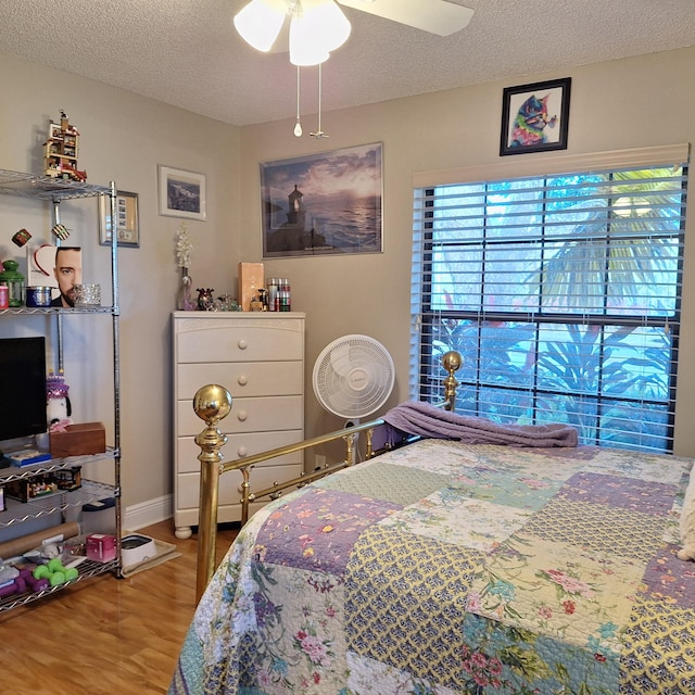 bedroom with a textured ceiling, wood finished floors, a ceiling fan, and baseboards