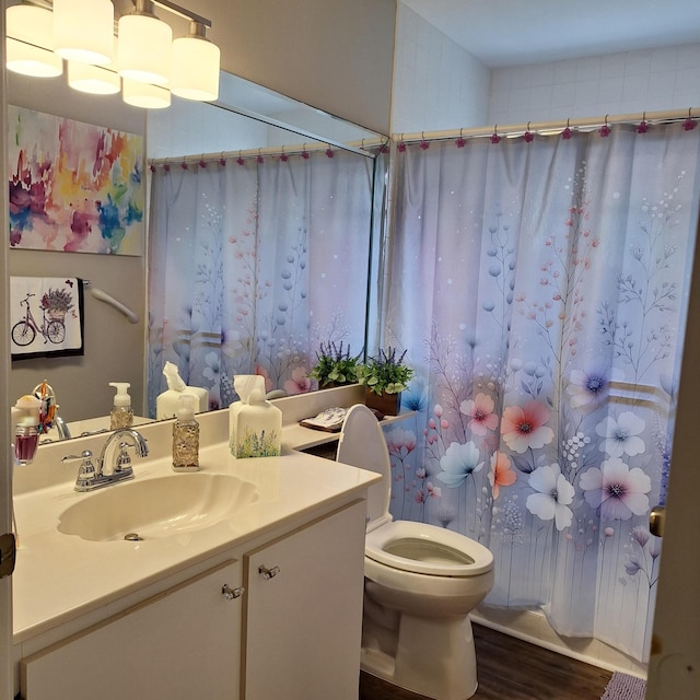 bathroom with toilet, a shower with shower curtain, wood finished floors, and vanity