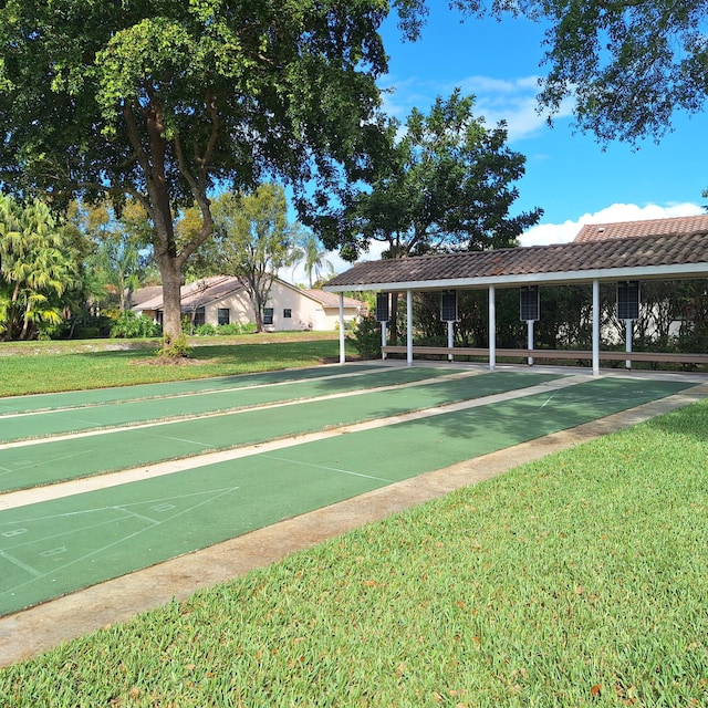 view of home's community with shuffleboard and a lawn