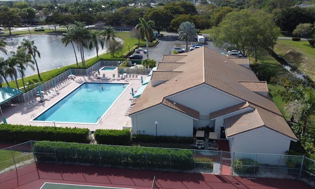 community pool featuring a patio area, a water view, and fence