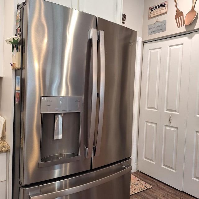kitchen with dark wood-type flooring, white cabinetry, stainless steel refrigerator with ice dispenser, and light stone counters
