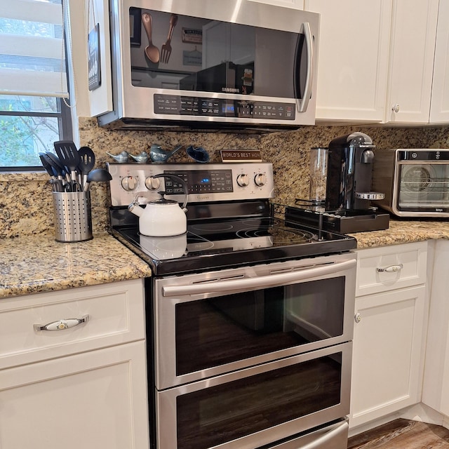 kitchen with light stone countertops, white cabinetry, tasteful backsplash, and appliances with stainless steel finishes