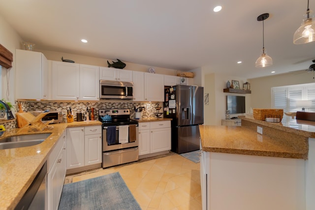 kitchen with appliances with stainless steel finishes, white cabinetry, a sink, and decorative backsplash