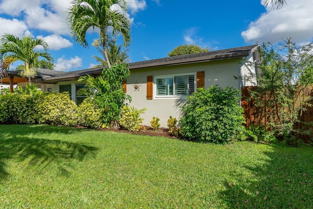 view of side of property with a yard, fence, and stucco siding