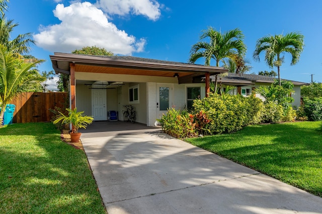 view of front of property featuring an attached carport, driveway, a front lawn, and fence