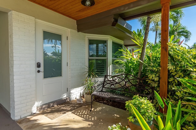 property entrance with a porch and brick siding