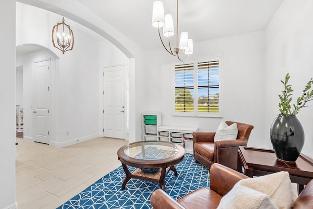 living area with baseboards, arched walkways, a chandelier, and wood finished floors