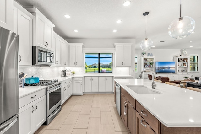 kitchen featuring stainless steel appliances, tasteful backsplash, light countertops, white cabinetry, and a sink