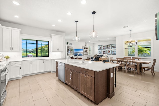 kitchen featuring a center island with sink, white cabinets, appliances with stainless steel finishes, light countertops, and a sink