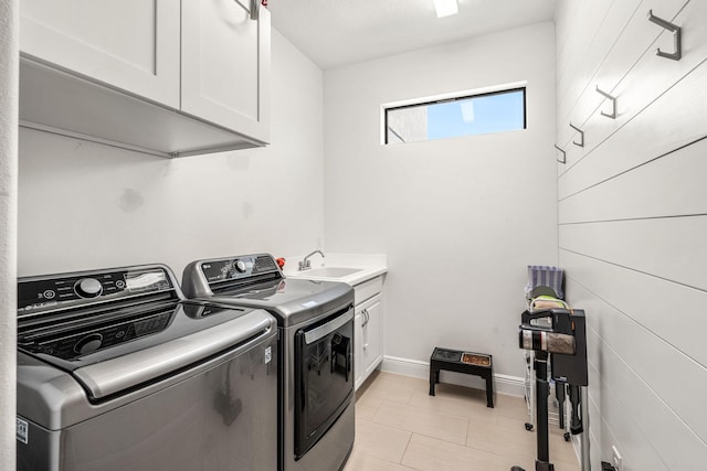 laundry area with cabinet space, light tile patterned floors, baseboards, washer and clothes dryer, and a sink