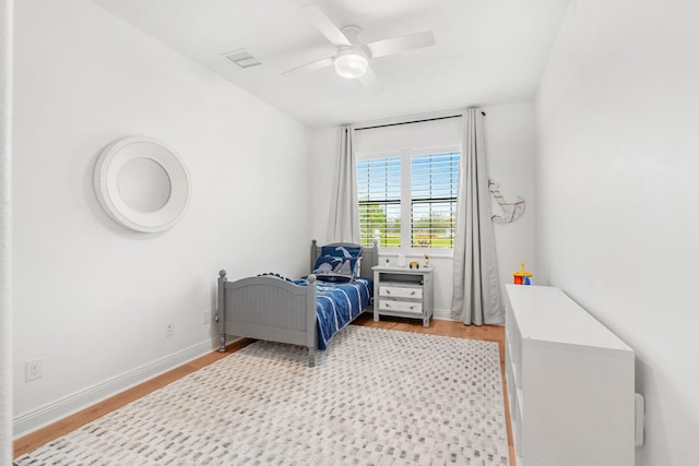 bedroom with light wood-style floors, visible vents, baseboards, and a ceiling fan