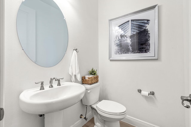 bathroom with a sink, wood finished floors, toilet, and baseboards