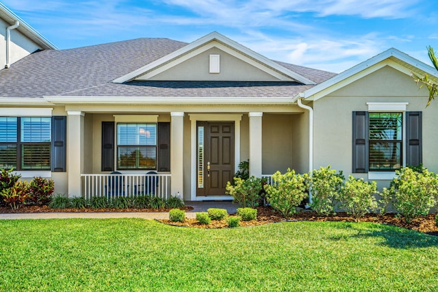 view of front facade featuring a shingled roof, a front lawn, a porch, and stucco siding