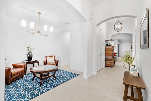 sitting room featuring arched walkways, a notable chandelier, and baseboards