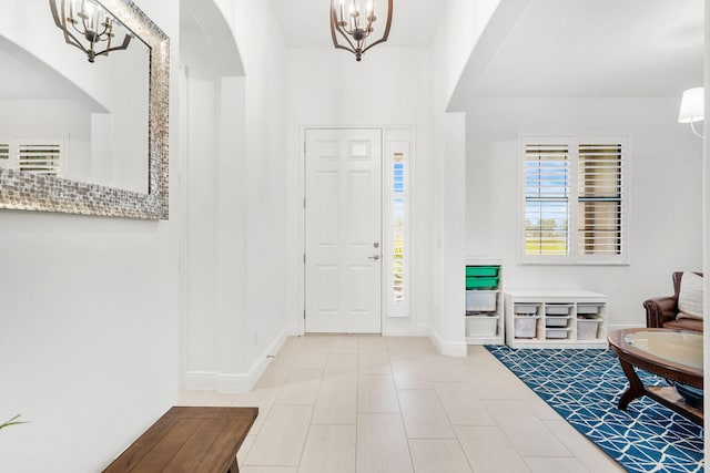 entryway with baseboards, arched walkways, and a chandelier