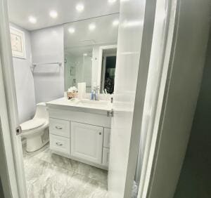 bathroom with toilet, marble finish floor, recessed lighting, and vanity