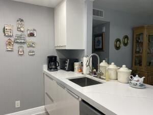 kitchen featuring visible vents, light countertops, a sink, and white cabinetry