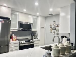 kitchen with white cabinets, stainless steel appliances, a sink, and recessed lighting