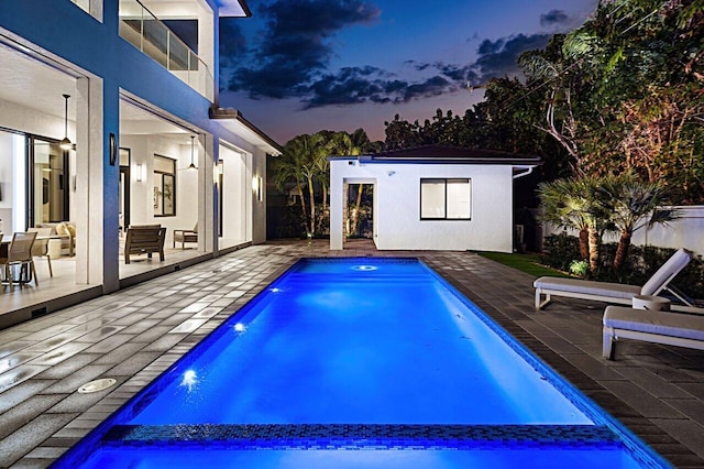 pool with a storage structure, an outdoor structure, and a patio