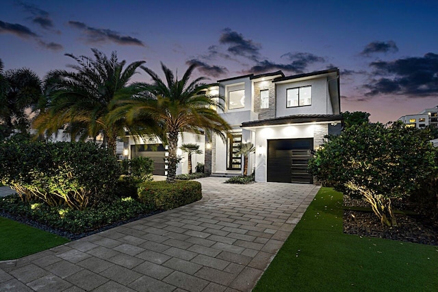 contemporary home featuring a garage, decorative driveway, and stucco siding