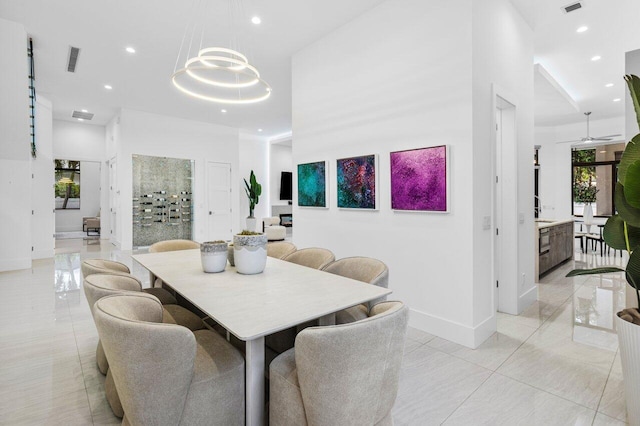 dining space with recessed lighting, visible vents, baseboards, a towering ceiling, and an inviting chandelier