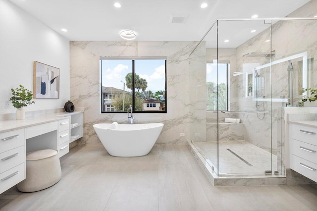 full bath featuring tile walls, a marble finish shower, recessed lighting, a soaking tub, and vanity