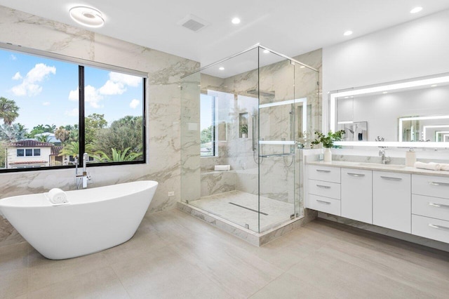 bathroom with a freestanding tub, a marble finish shower, vanity, and recessed lighting