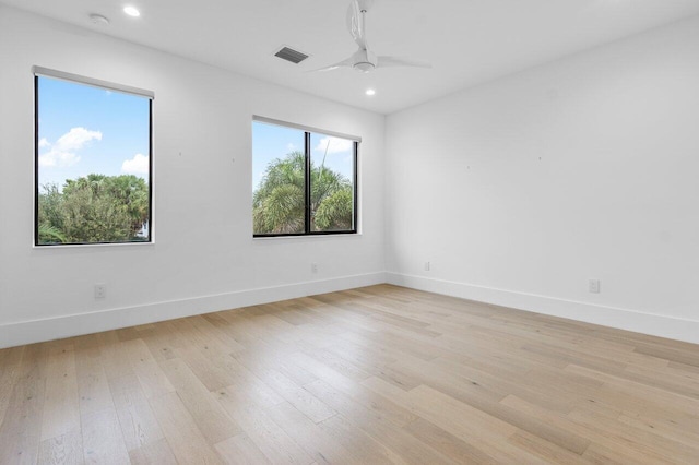 unfurnished room with a ceiling fan, visible vents, light wood-style flooring, and baseboards