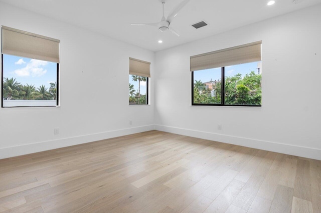 spare room with light wood-type flooring, baseboards, visible vents, and a ceiling fan