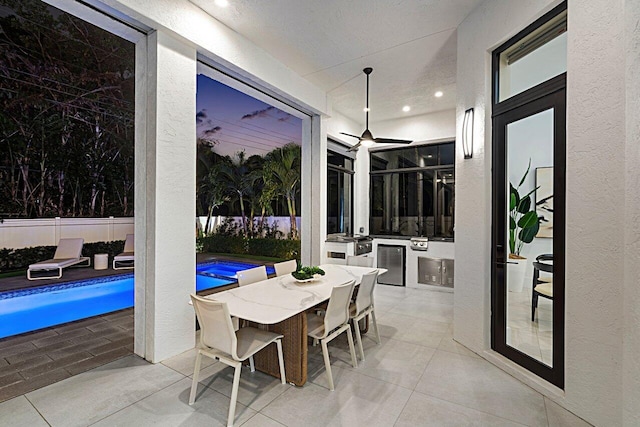 view of patio / terrace with a fenced in pool, ceiling fan, fence, outdoor dining area, and exterior kitchen