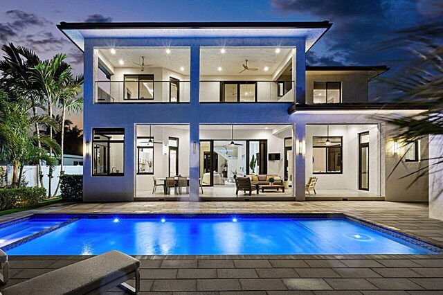 rear view of property with ceiling fan, a balcony, fence, an outdoor living space, and stucco siding