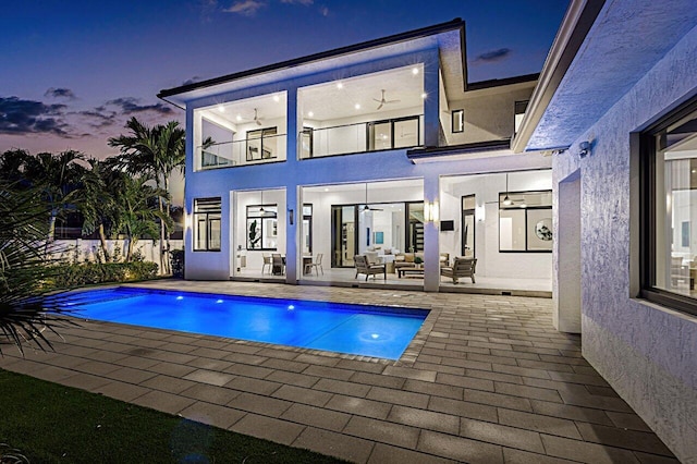 back of property featuring a patio area, an outdoor hangout area, a fenced in pool, and stucco siding