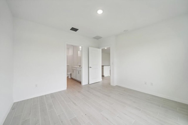 empty room featuring light wood-style floors, recessed lighting, visible vents, and baseboards