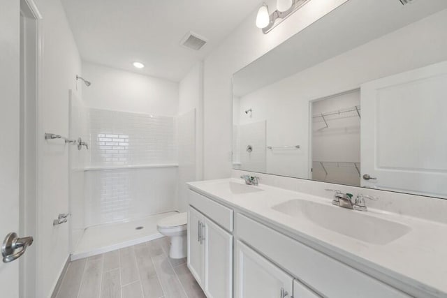 bathroom featuring a stall shower, visible vents, a sink, and toilet