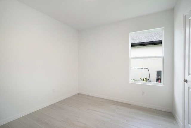 unfurnished room featuring baseboards and light wood finished floors