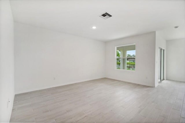 unfurnished room featuring light wood-type flooring, visible vents, and baseboards