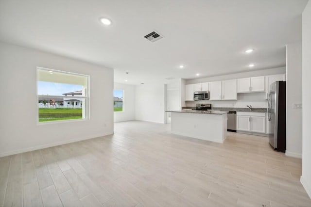 kitchen featuring stainless steel appliances, dark countertops, visible vents, open floor plan, and white cabinetry