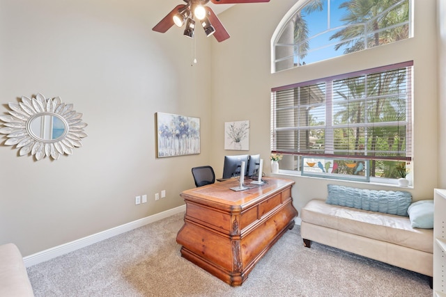 carpeted office featuring ceiling fan, a towering ceiling, and baseboards